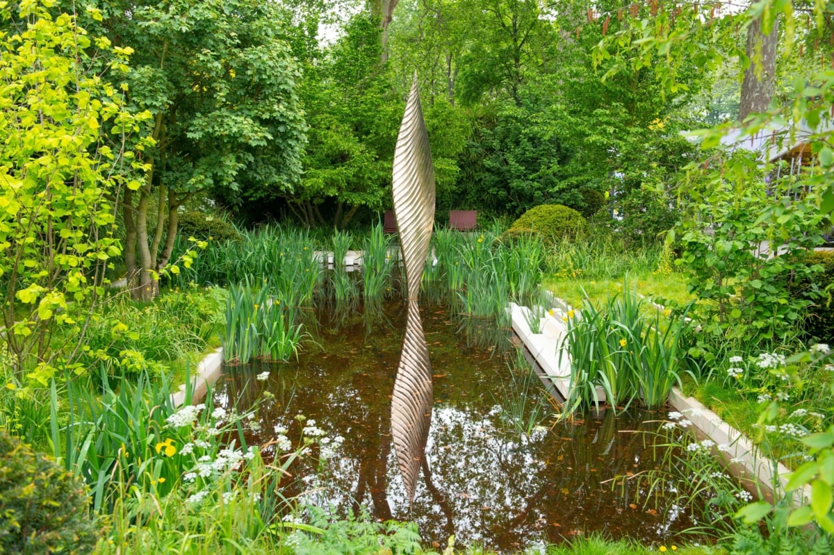 Schwimmteich Idee mit Schilf und moderner Skulptur im Wasser