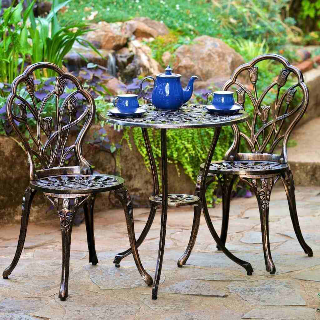 Stühle und Tisch aus Schmiedeeisen mit Vintage-Geschirr auf Steinboden