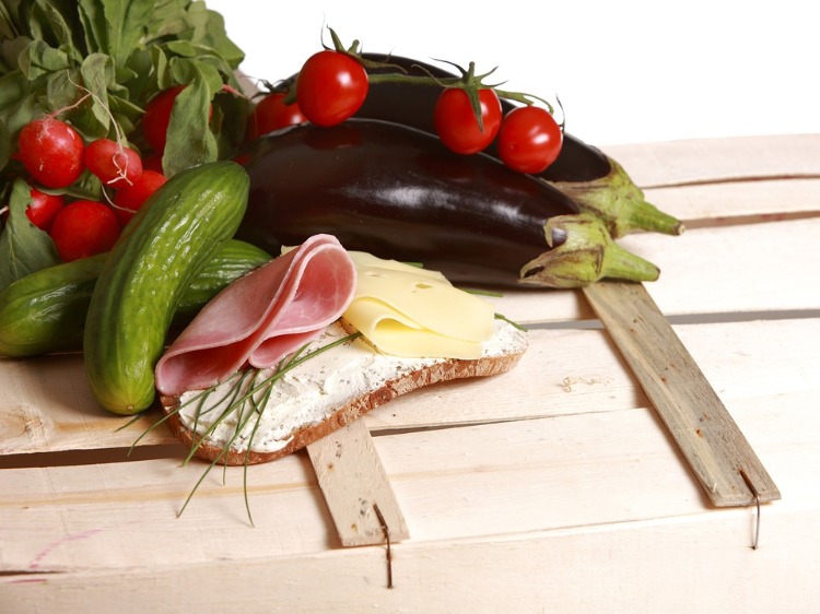 brot mit frischkäse schinken lauch käse neben gurken und radieschen