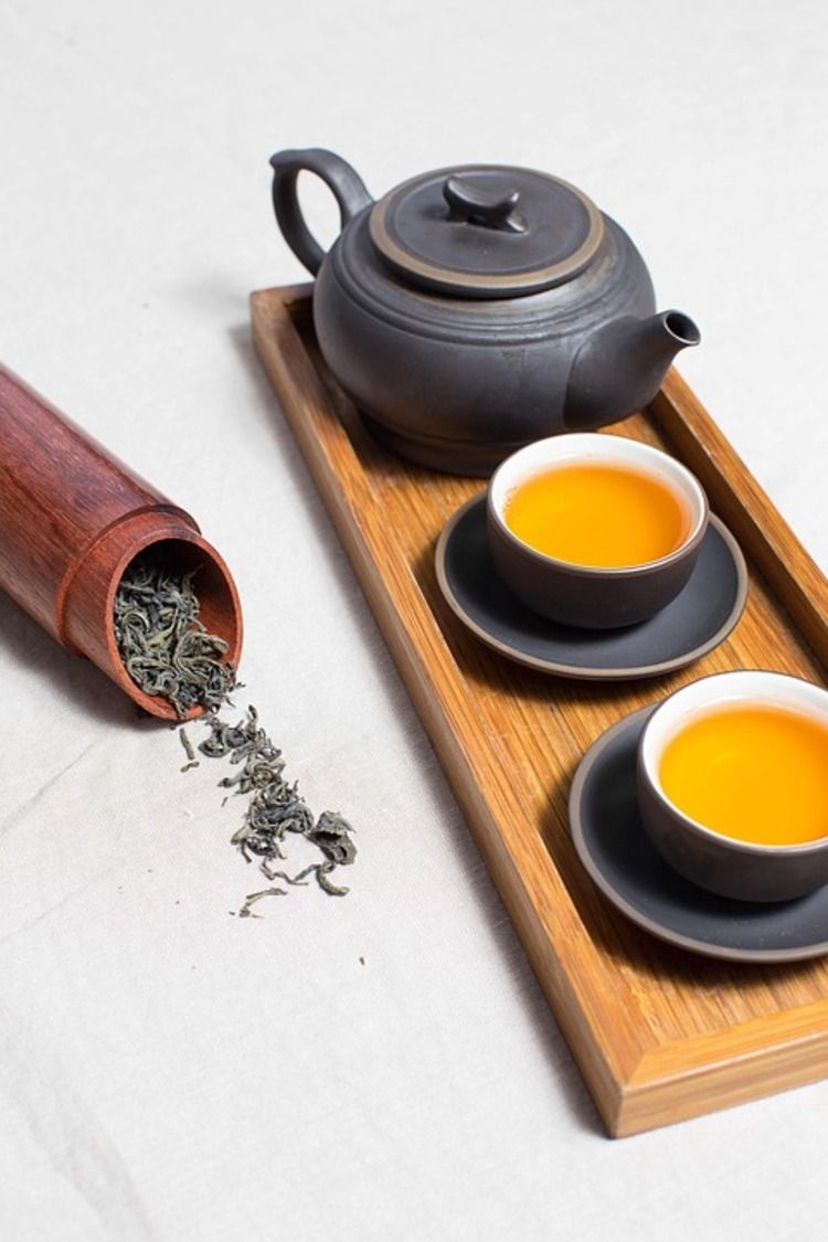 getrockneter koffeinhaltiger tee in bambus und zwei tassen mit kanne