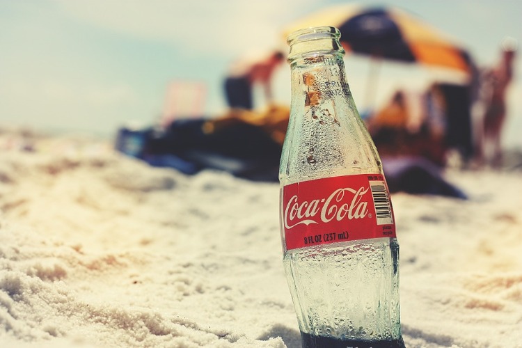 leere coca cola flasche im sand auf dem strand