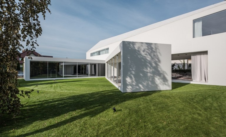 weiß und grau Fassade Gartenhaus anliegend Haus zwei Bauvolumen Schiebetüren Glasfronten