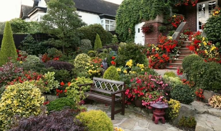 Üppig bepflanzter Cottage Garten mit dezent geformten Büschen