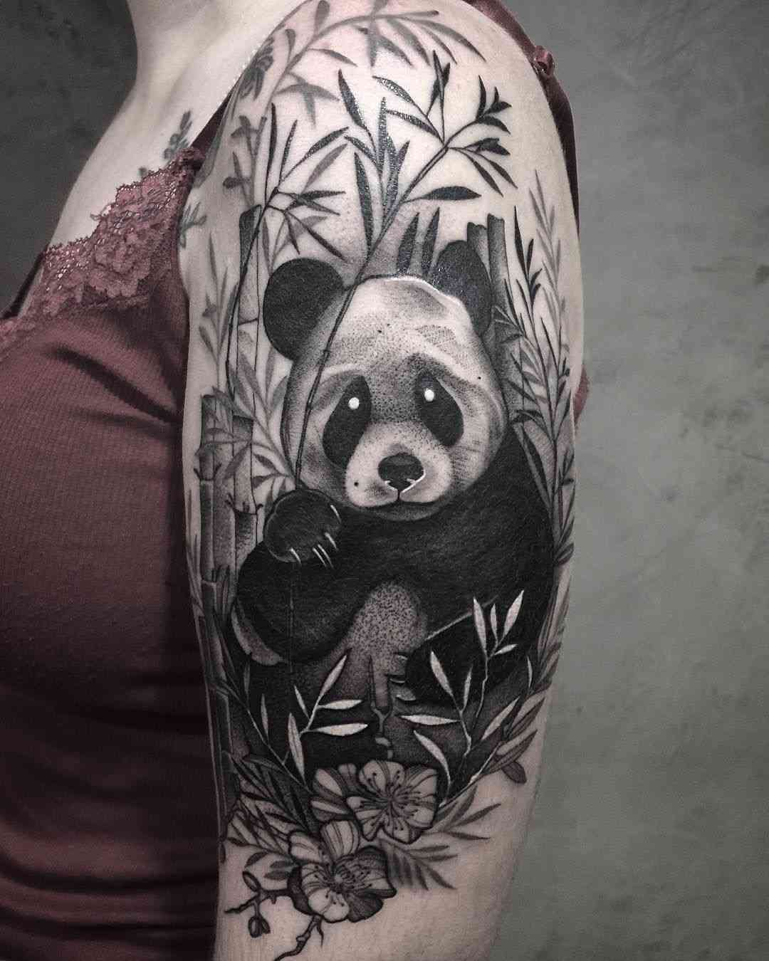3D Oberarmtattoo im Blackwork Design mit Panda mitten im Bambus