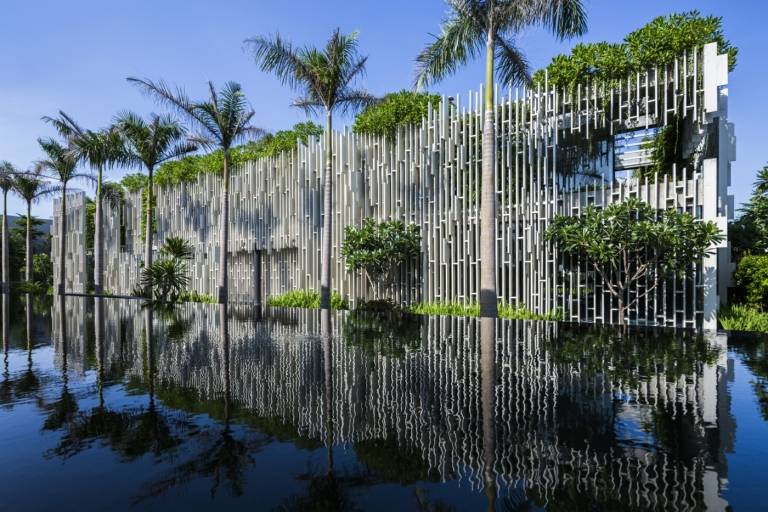Das Gebäude mit grüner Fassade ist von einem großen Teich umgeben