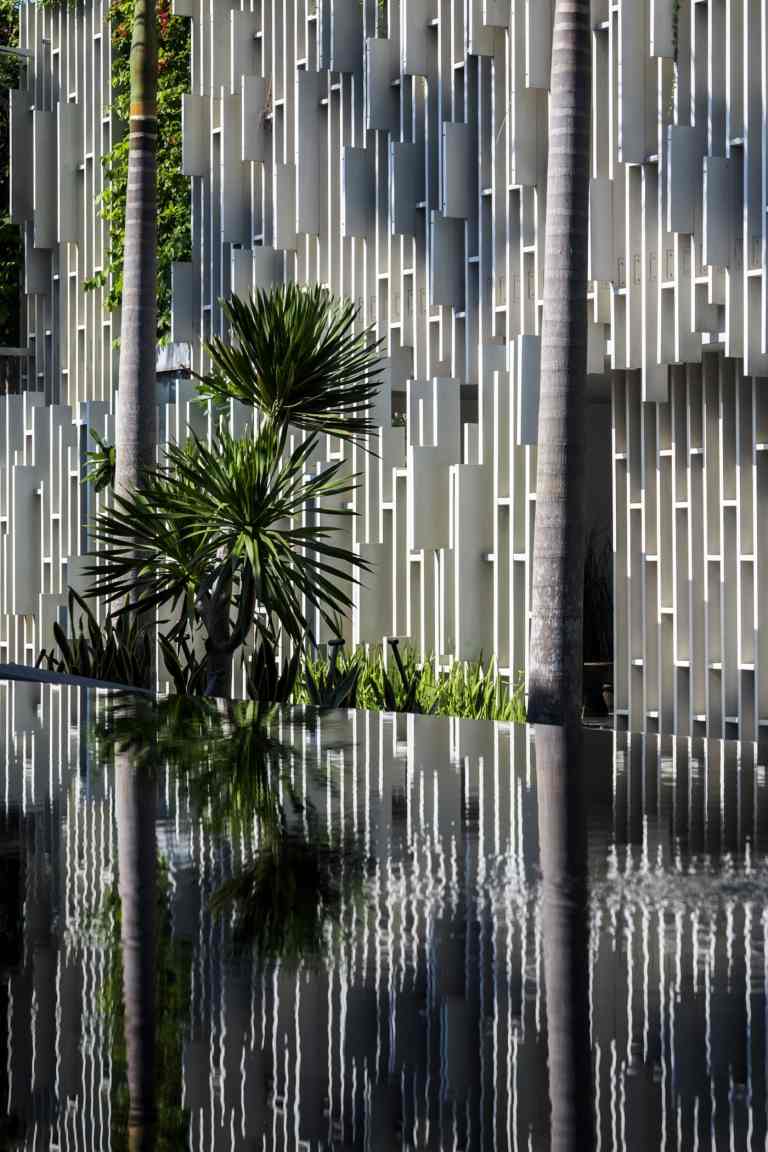 Der Außenbereich um das Gebäude herum gleicht mit seinem Teich und den Palmen einer Oase