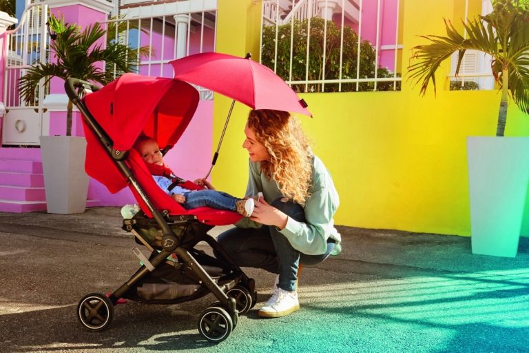 Kinderwagen mit kleinen Rädern und rotem Sonnenschirm