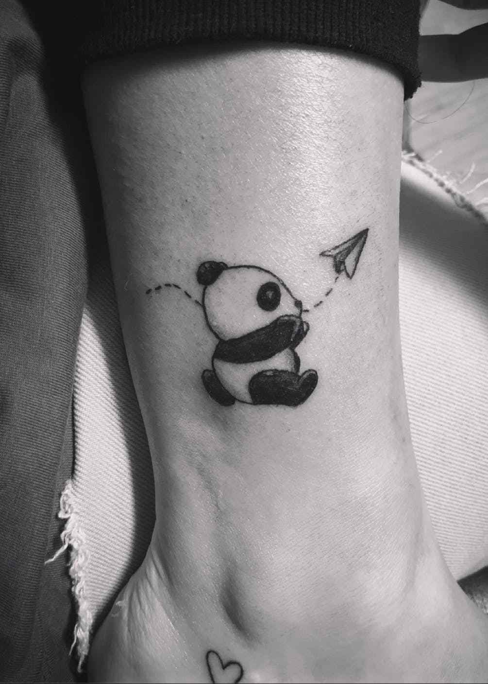 Kleiner Panda spielt mit einem Papierflugzeug - Mini-Tattoo für das Fußgelenk