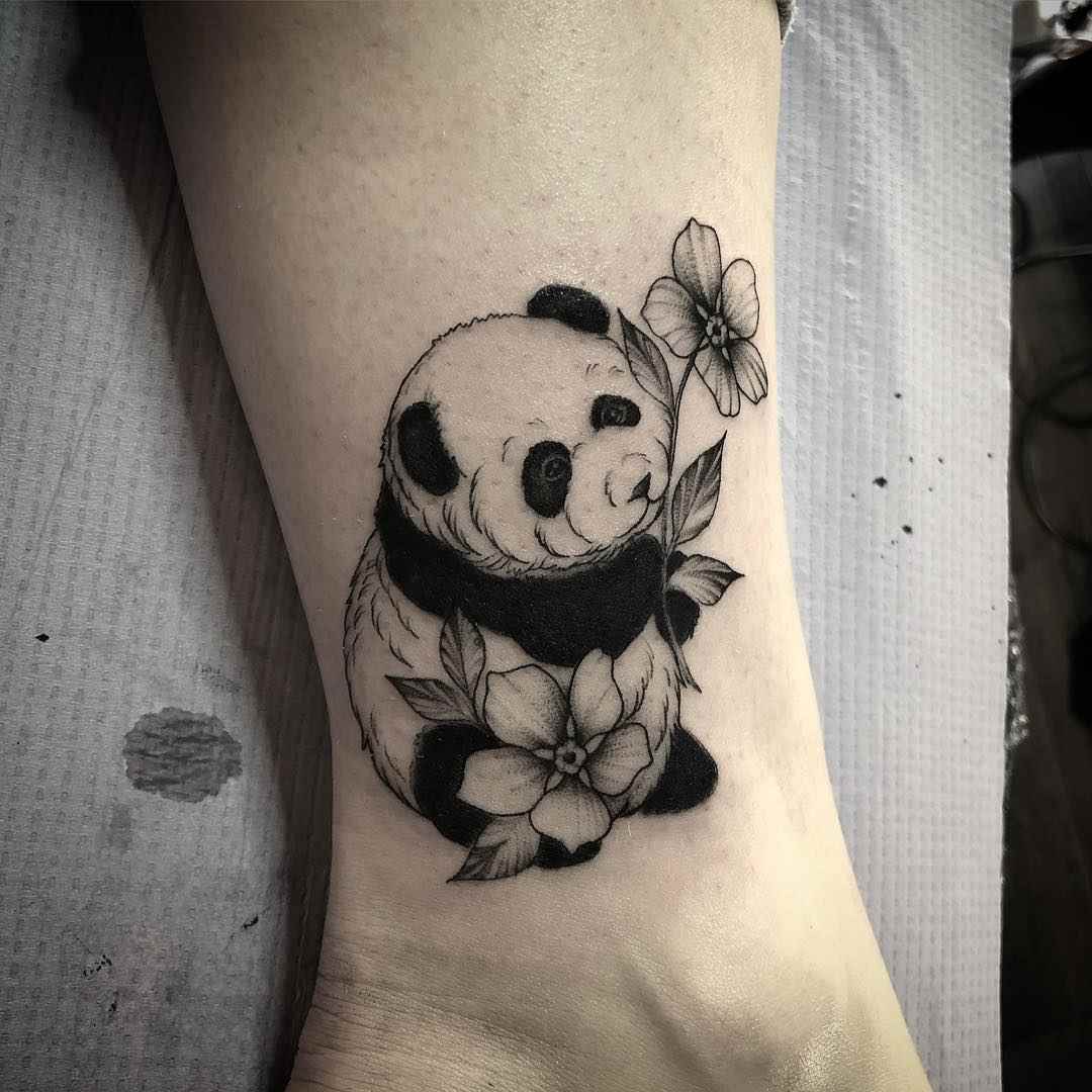 Panda mit Blüten über dem Knöchel einer Frau