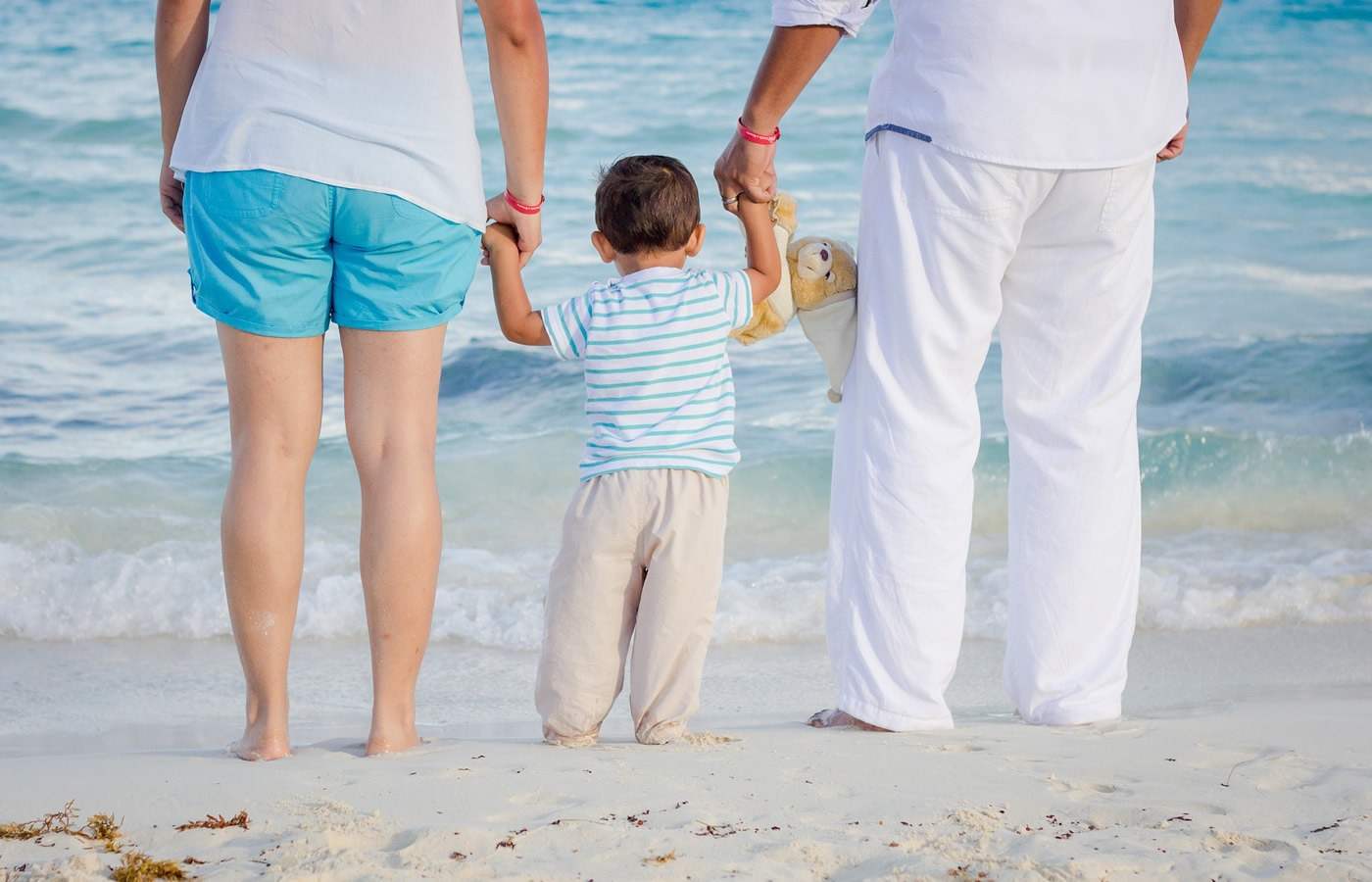 familie aus frau und mann mit kind in sommerbekleidung für den strand
