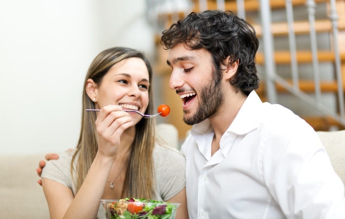 frau reicht ihrem partner i kirschtomate aus salatschüssel für bessere kohlenhydrataufnahme