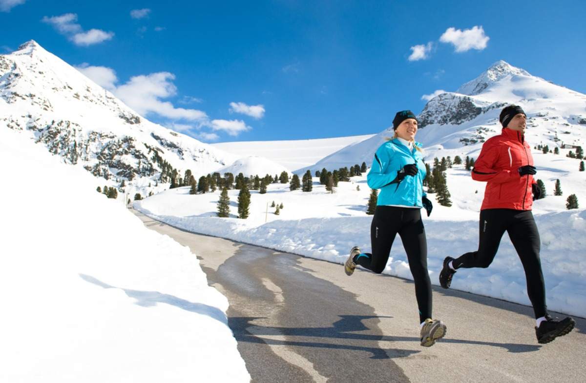 frau und mann jogging in winter swiss snow and mountains