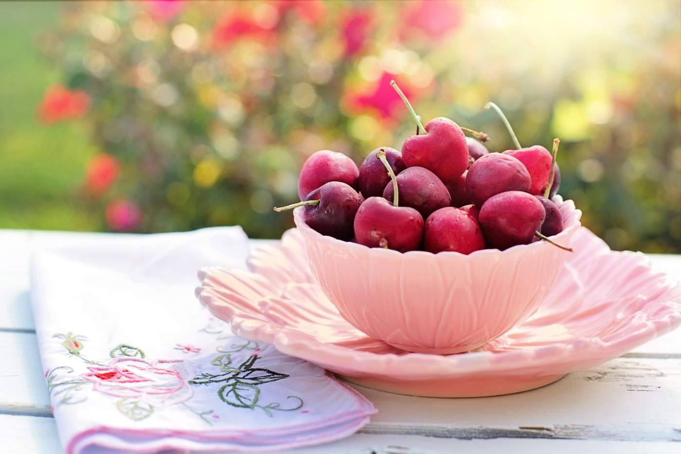frische kirschen in rosafarbener schüssel auf einem tisch am warmen tag