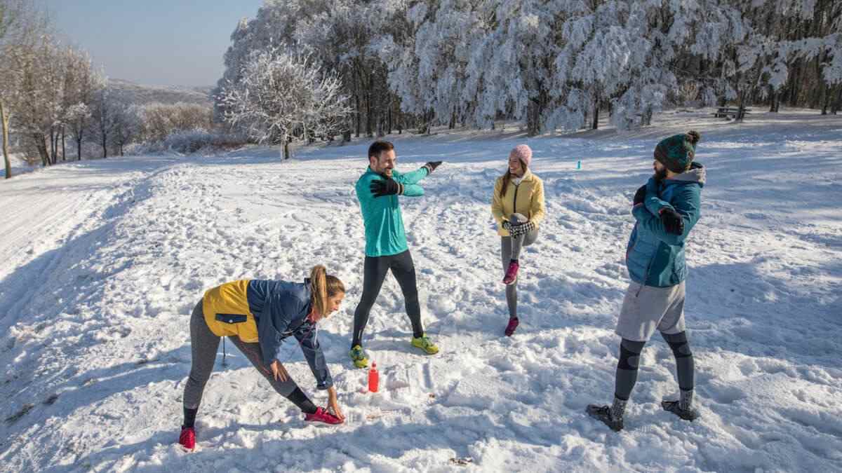 group of young people power stretching in snow in winter urlaub