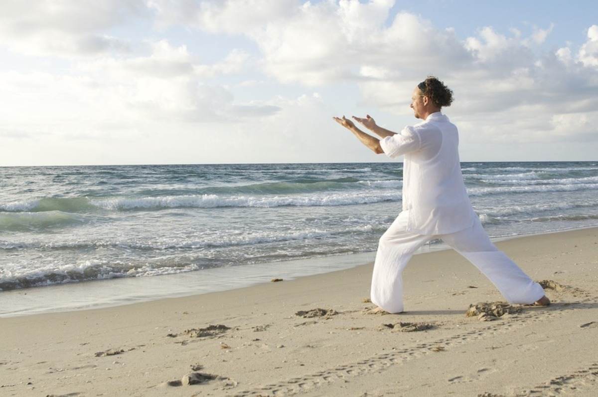 mann in weißer bekleidung macht yoga am strand