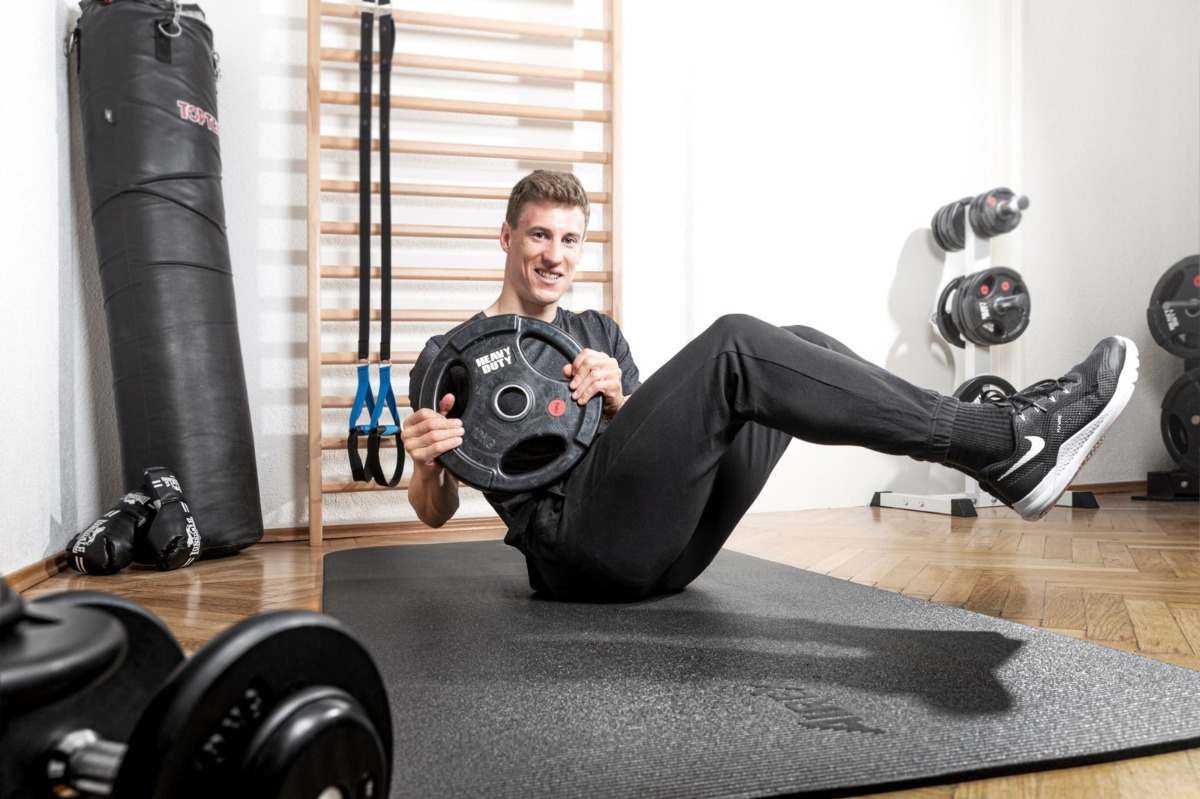 mann verwendet gewicht für ausführung von russian twist im fitnessstudio