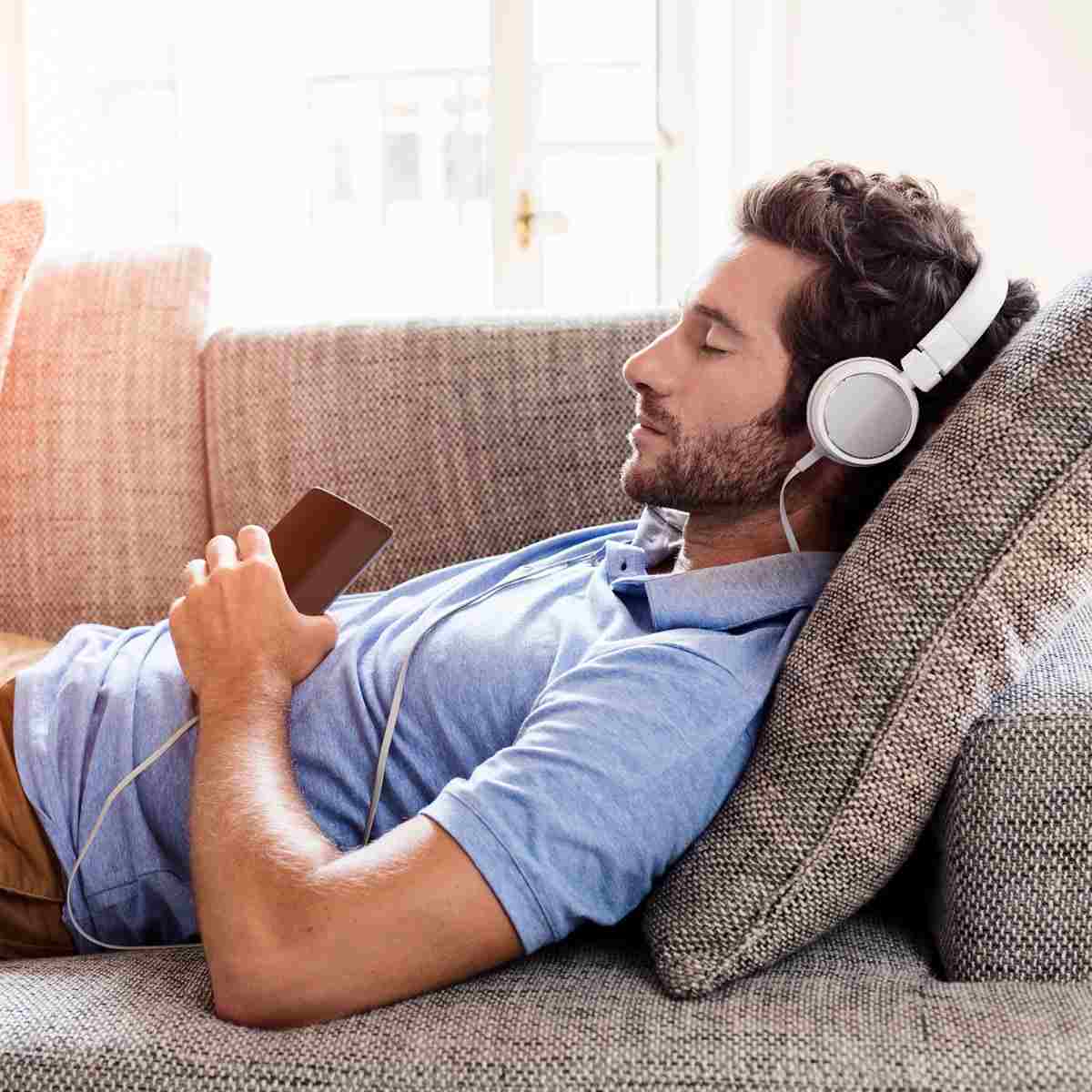 zuhause auf dem sofa mit kopfhörern relaxieren und stress reduzieren