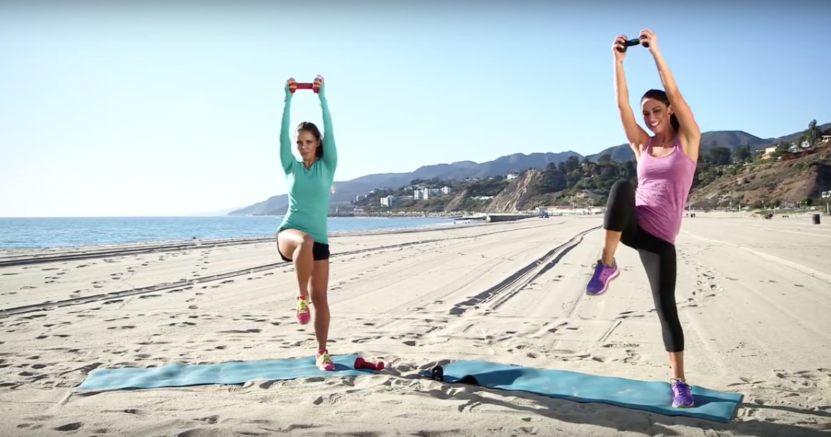 two women in the beach with foam rolls and weights