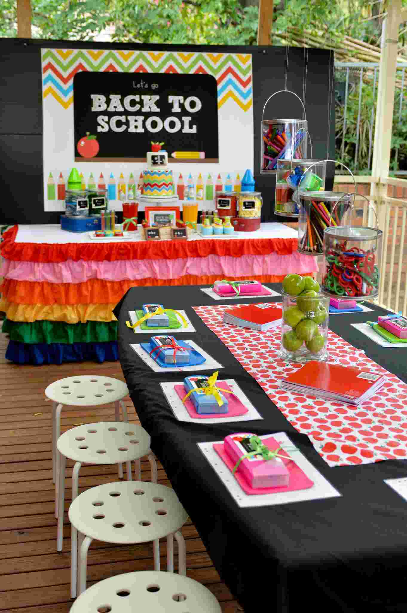 Einschulungsparty im Freien planen mit Tisch für die Gäste und Desserttisch in Regembogenfarben