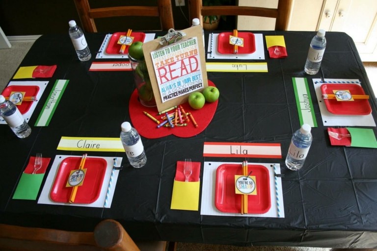 Schwarze Tischdecke imitiert Tafel und hebt die bunten Pappteller und die Tischdeko hervor