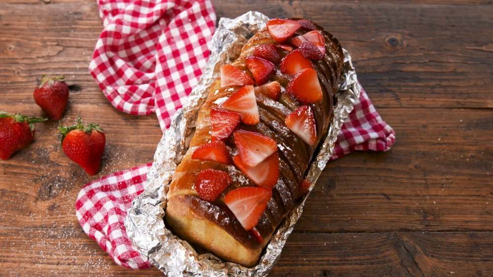 appetitlich aussehendes süßes brot mit erdbeeren in alufolie umwickelt für camping kochen dessert oder frühstück
