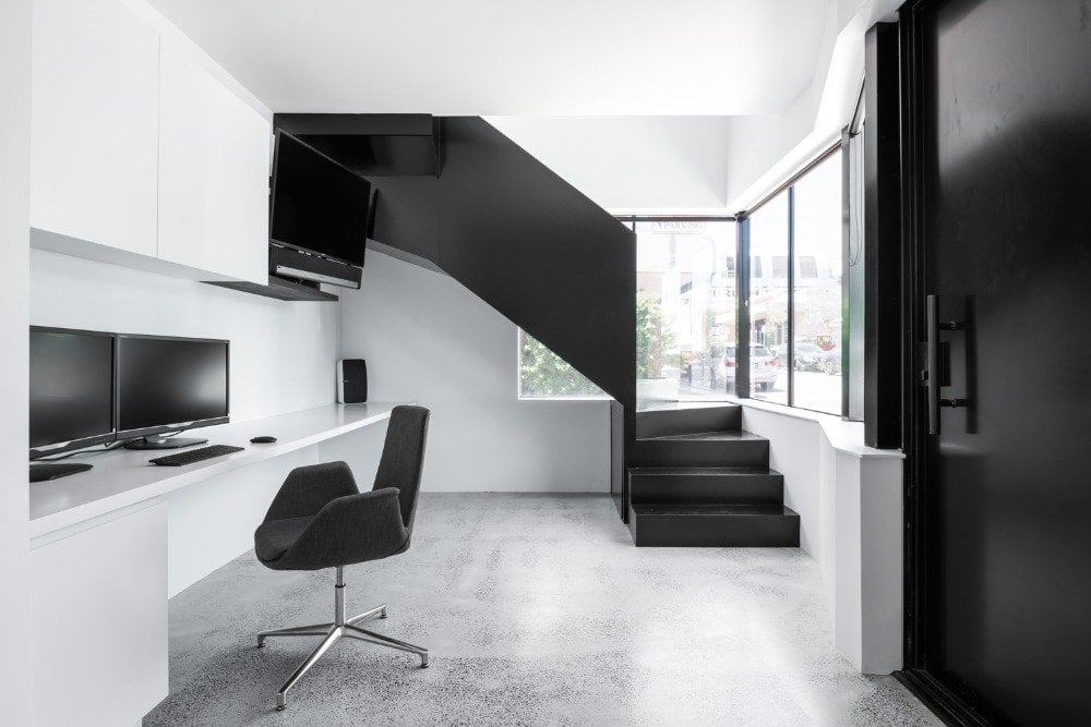 arbeitszimmer mit stuhl und monitoren in schwarz weiß mit betonboden