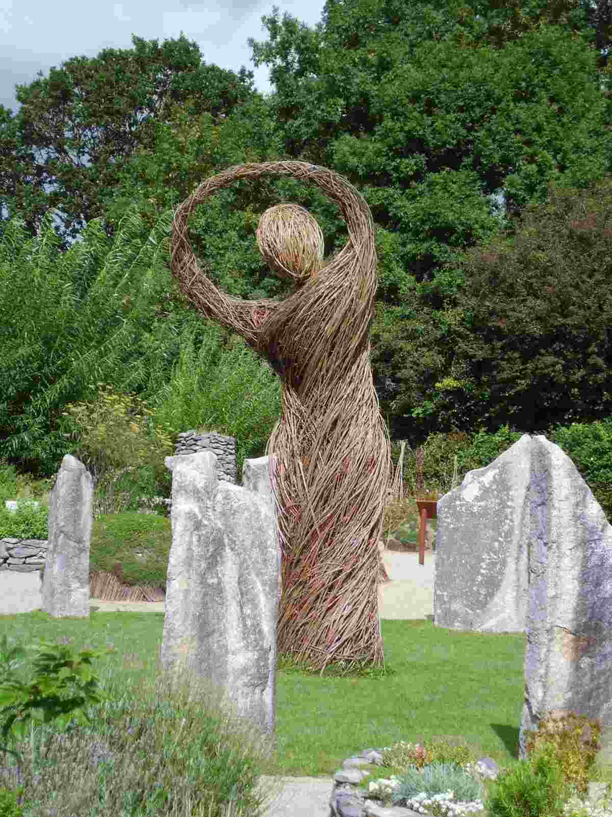 position a woman figure as a centerpiece in the garden next to stones