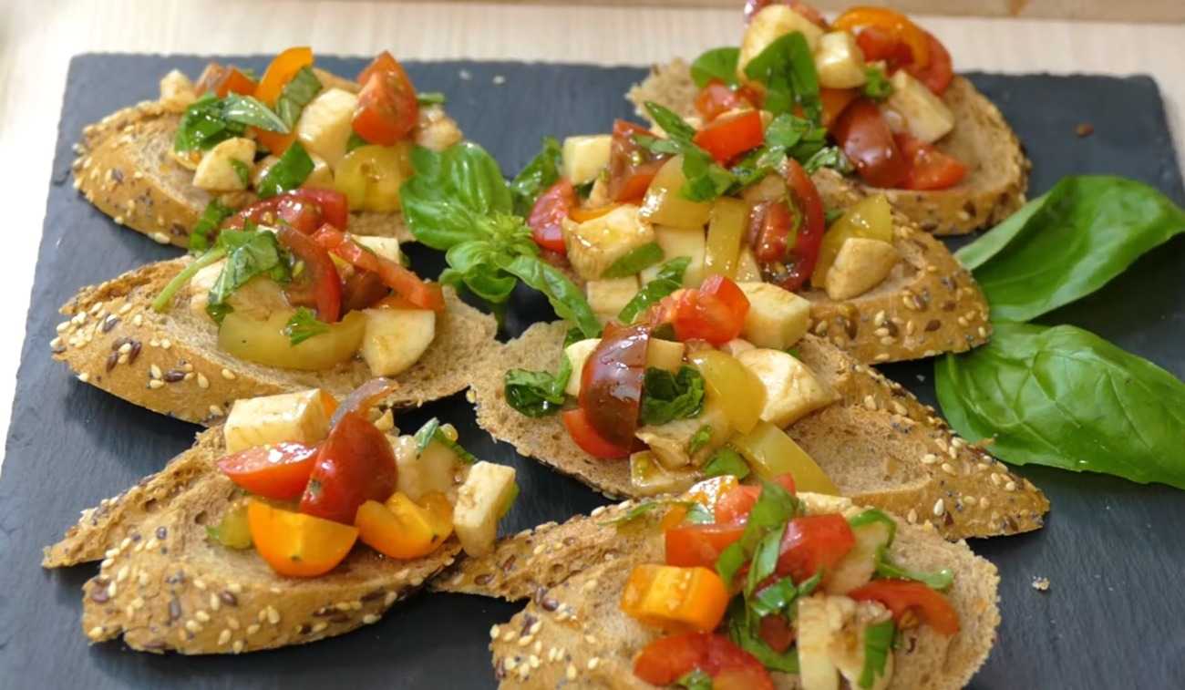 Finger food is quickly prepared as bruschetta with tomatoes and mozzarella decorates with basil
