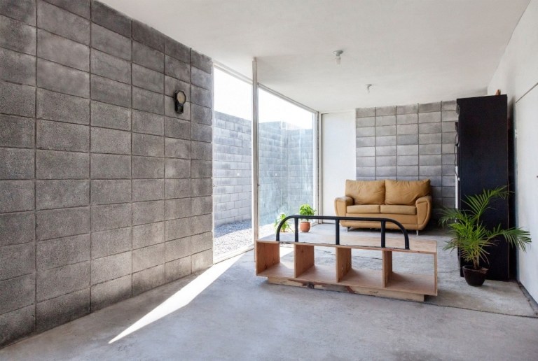günstig gebautes haus mit minimalistisch eingerichtetem wohnzimmer und wänden aus betönnblöcken
