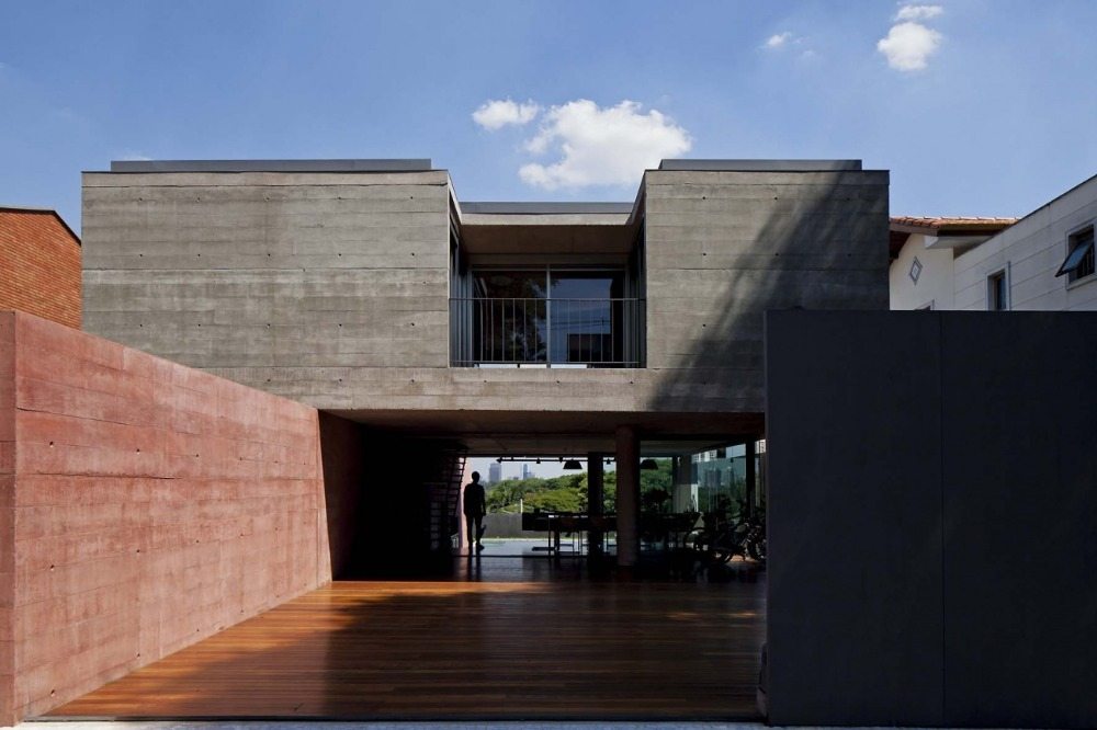 holzboden im außenbereich mit einer wand rot farbener beton in minimalistisch gebautem haus