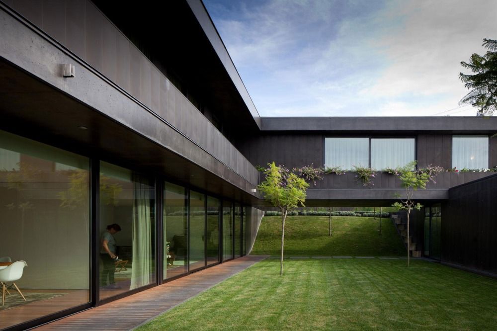 courtyard with a huge black facade and glass sliding doors in the first and second storey