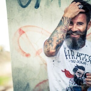 lachender mann mit bart und moderner frisur zeigt seine arm tattoos männer