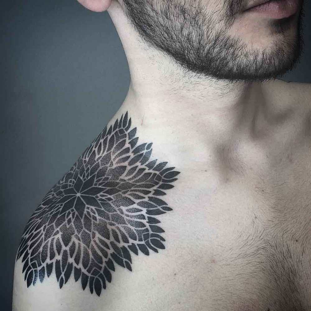 man with a floral pattern tattoo tattooed on the shoulder with black tint