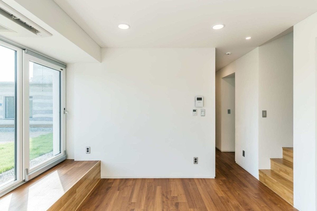 minimalistischer raum mit holzboden und weißen wänden sowie treppenhaus und deckenbeleuchtung