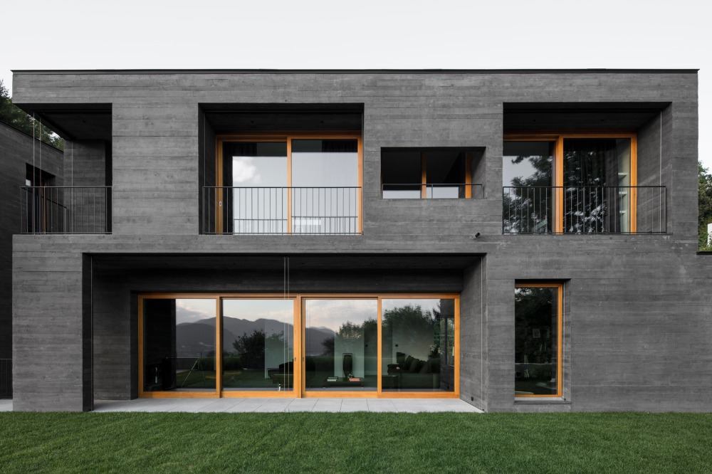 moderne villa aus schwarzem betonbau in kontrast mit holzrahmen von fenstern