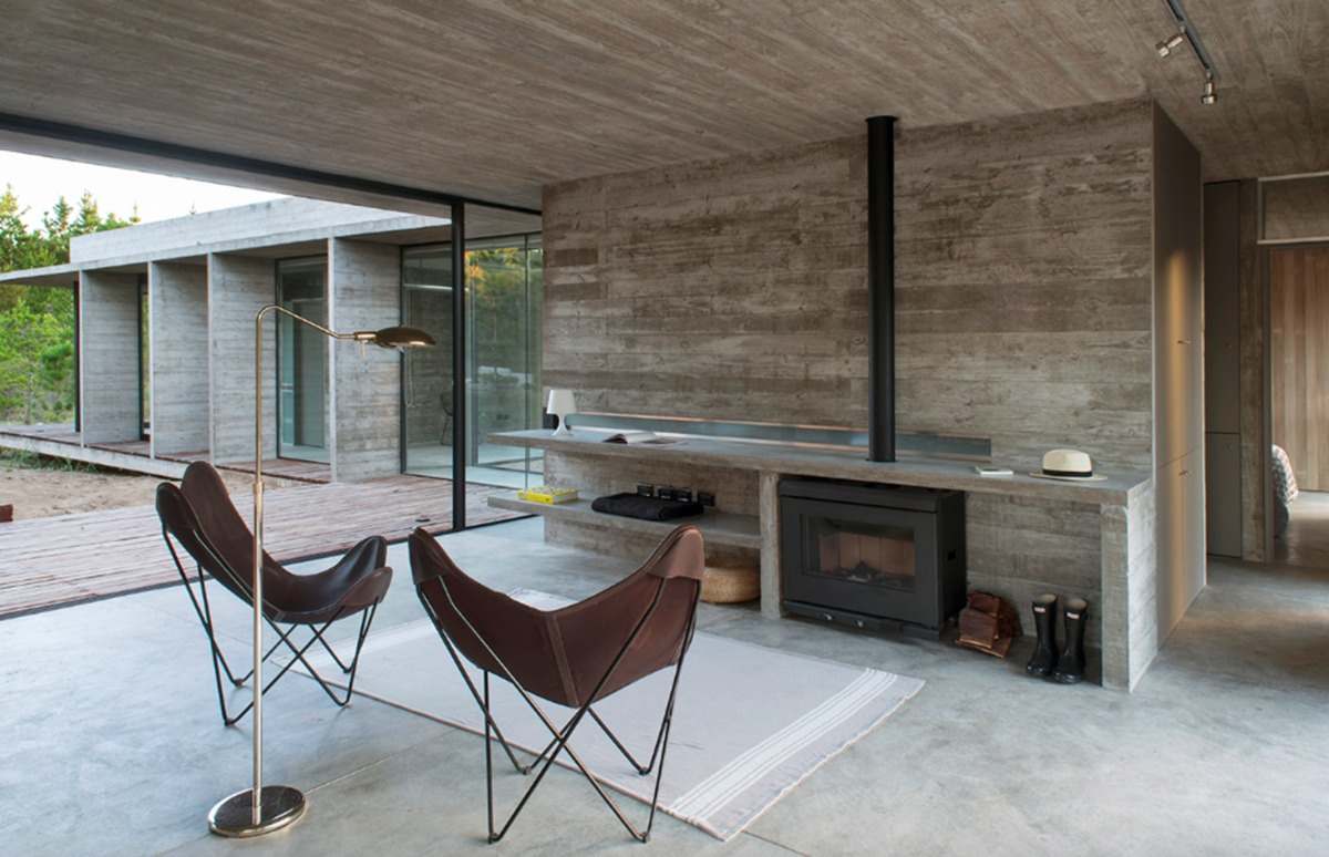 offener wohnraum mit kamin und designer stühlen mit betonboden und betondecke