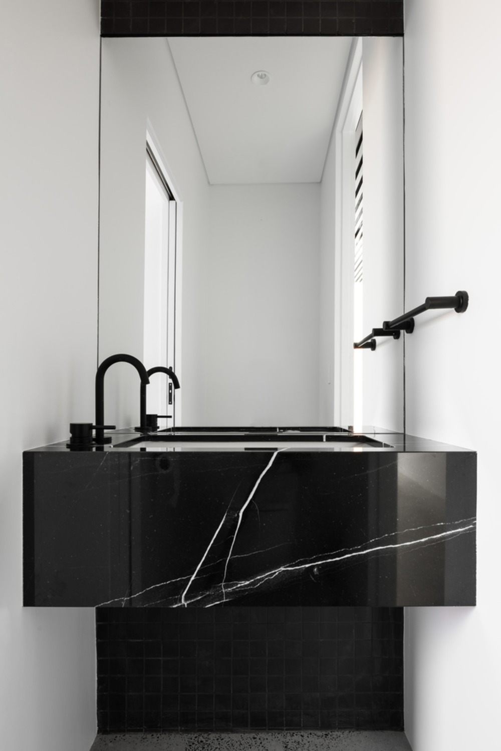 waschbecken in schwarz aus marmor mit spiegel im badezimmer