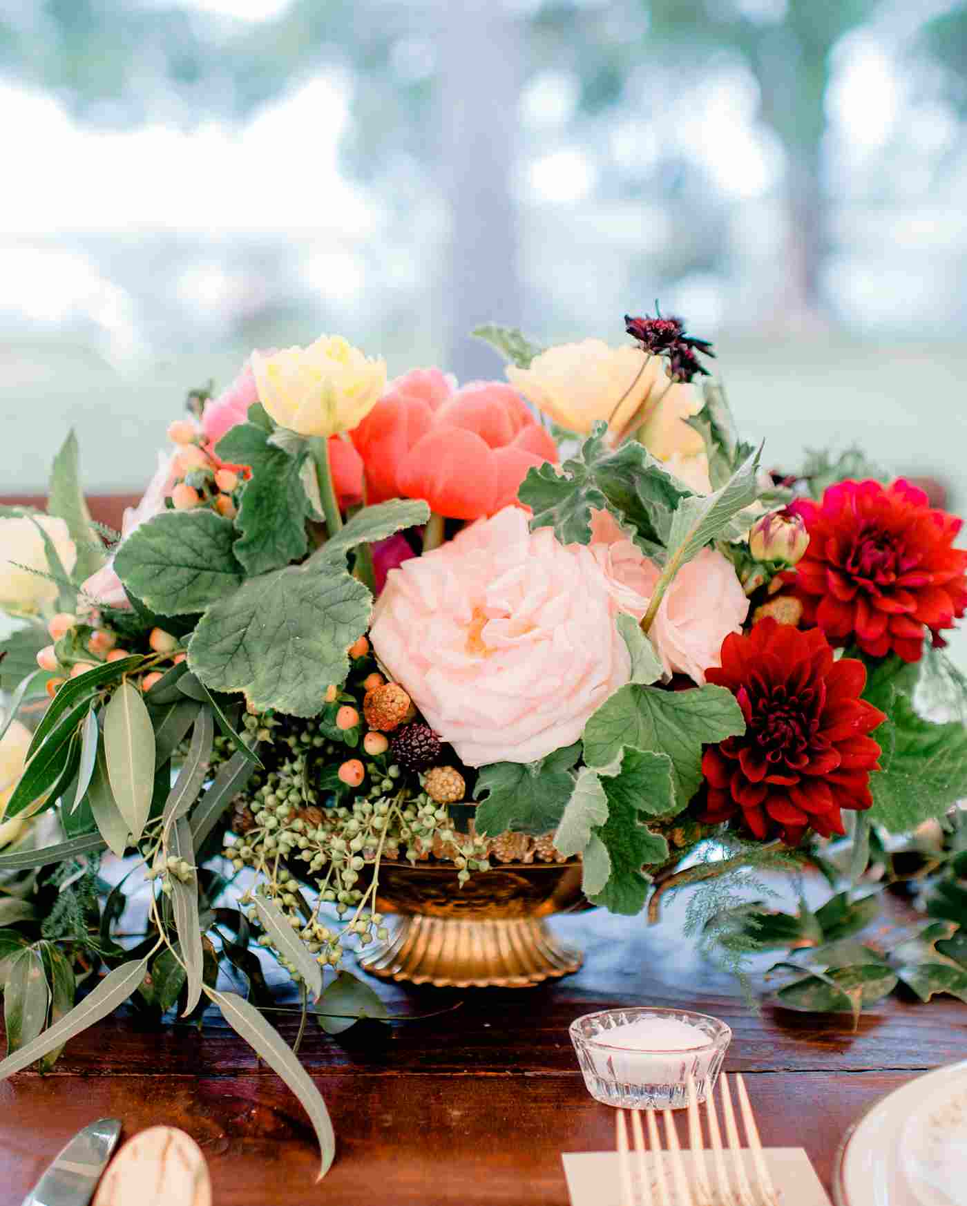 red autumn deco with seasonal flowers pink roses and red dahlias and pink peonies with ornamental grasses and deciduous leaves in a vintage golden vase