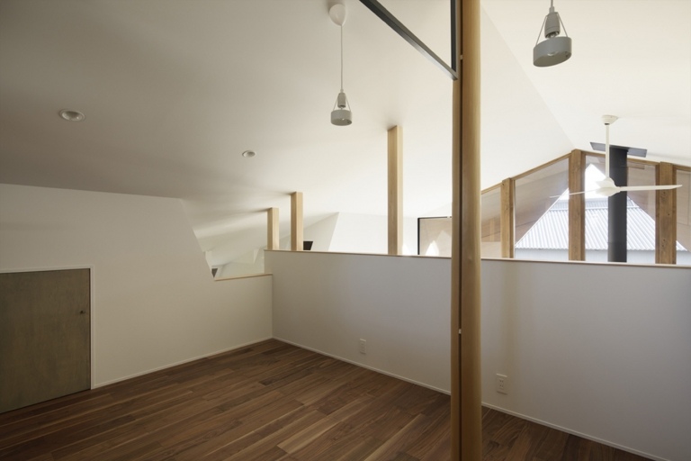 Raum unter einer Dachschräge mit Dielenboden und weißen Wänden