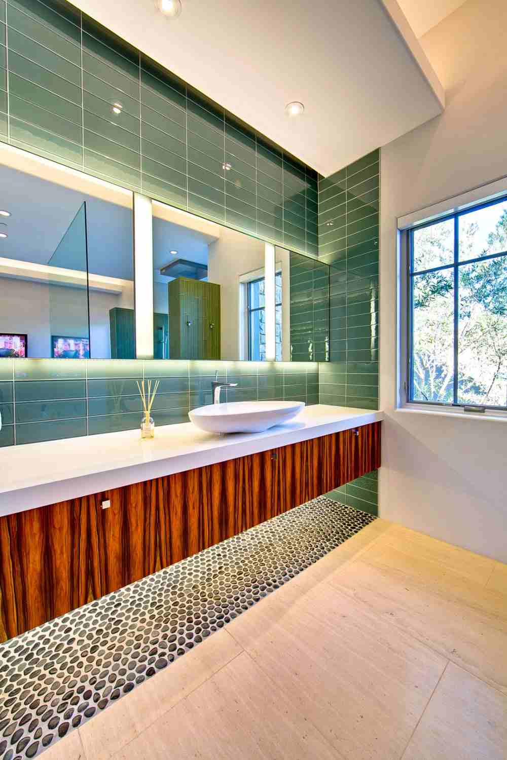 colorful bathroom design with green tiles and wooden pebbles in the bottom