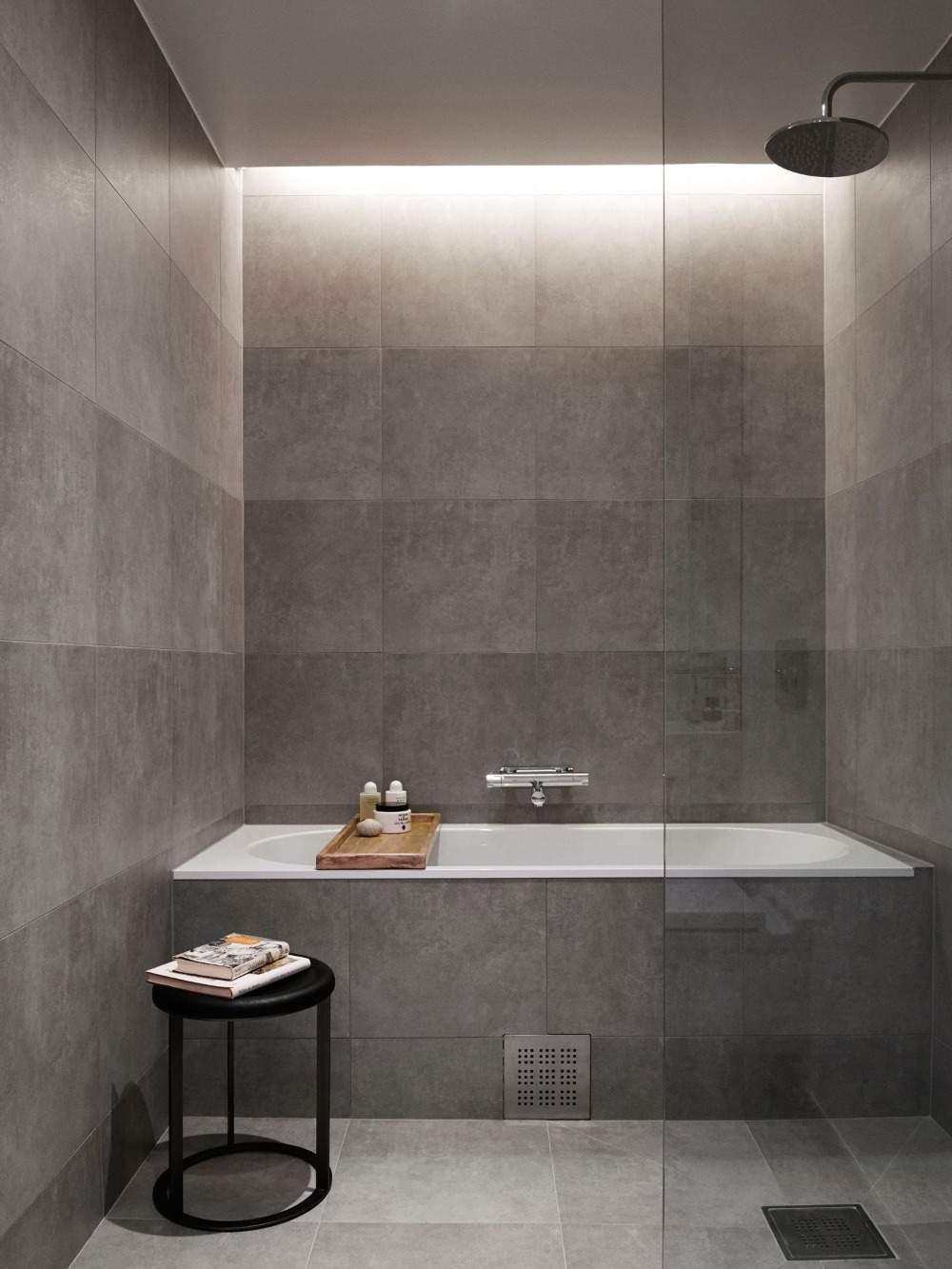 graues kleines bad beleuchtung an der decke über badewanne mit glastrennwand