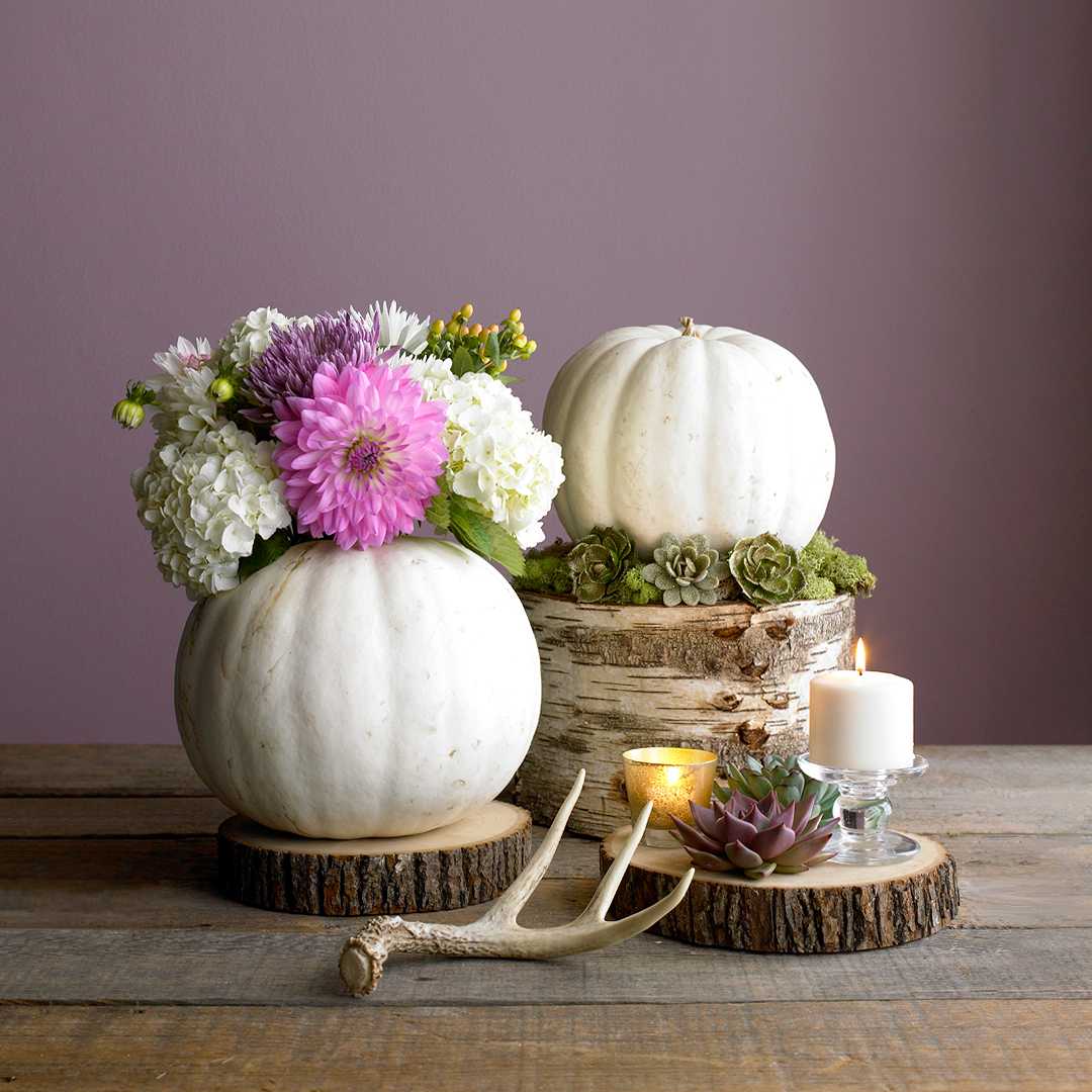 modern autumn table decoration in white and pink with dahlias and pumpkins and tree trunk vases