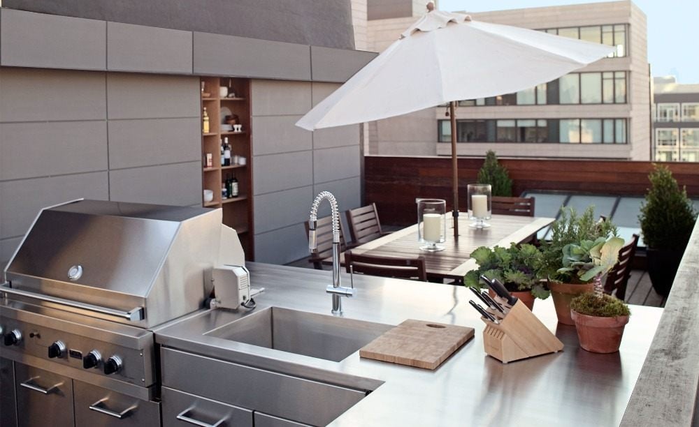 Practical kitchen made of stainless steel on roof terrace with modern design and plant-tops as well as sun screen