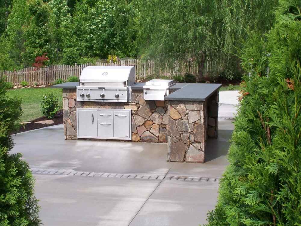 rustic kitchen island with stainless steel gas grill in the middle of the garden