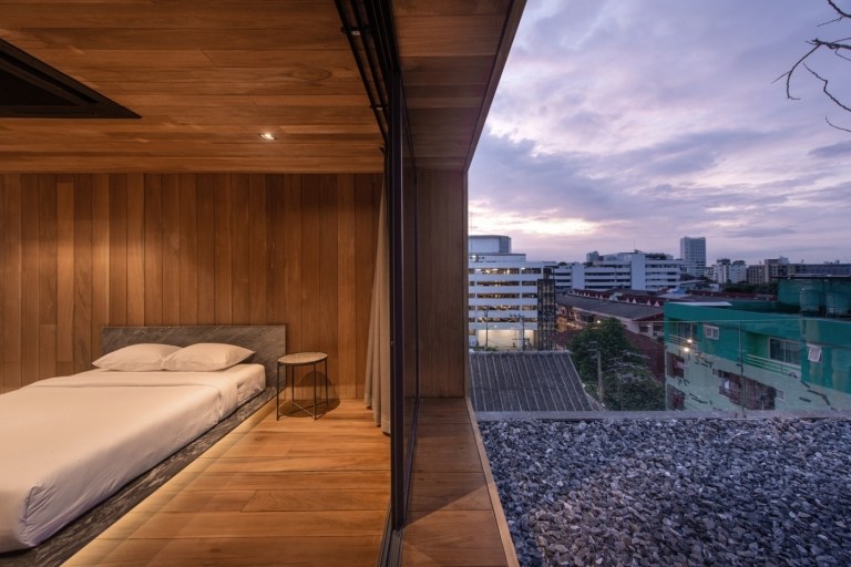 schlafzimmer mit doppelbett und glasschiebetür mit ausblick in wohnung auf dem dach