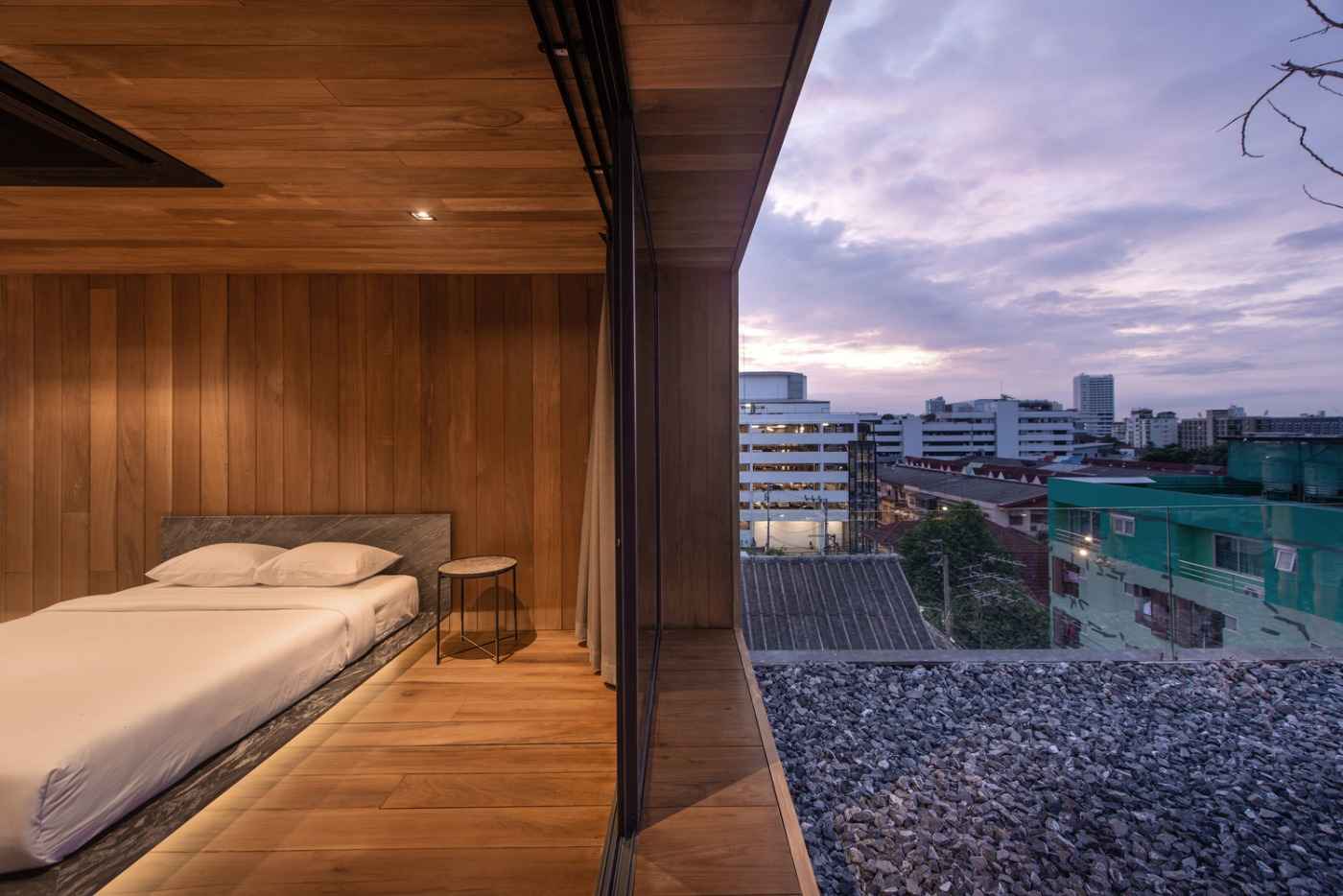 bedroom with double bed and glass sliding door with a view of apartment on the roof