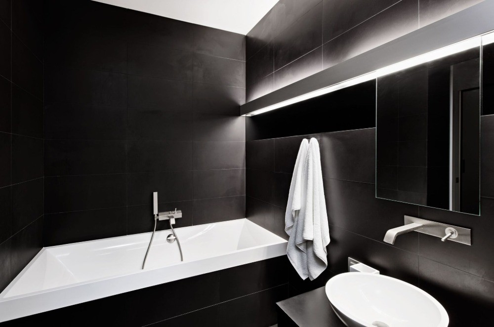 black tiles contrast with white light in the bathroom