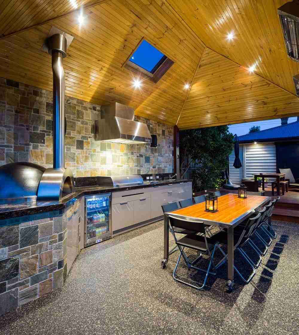 thoughtful outdoor kitchen with light window built-in refrigerator and aesthetically-pleasing pizza oven