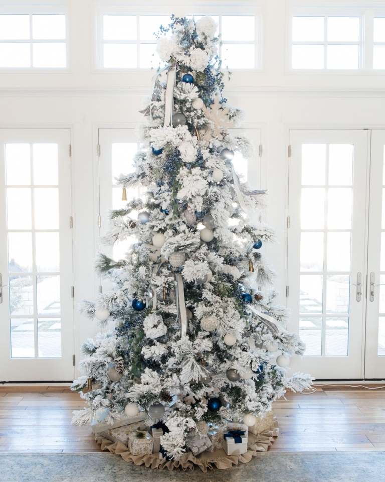 Christbaum weiß silber geschmückt Kunstschnee und dunkelblauen Kugeln und Präsente unter dem Weihnachtsbaum