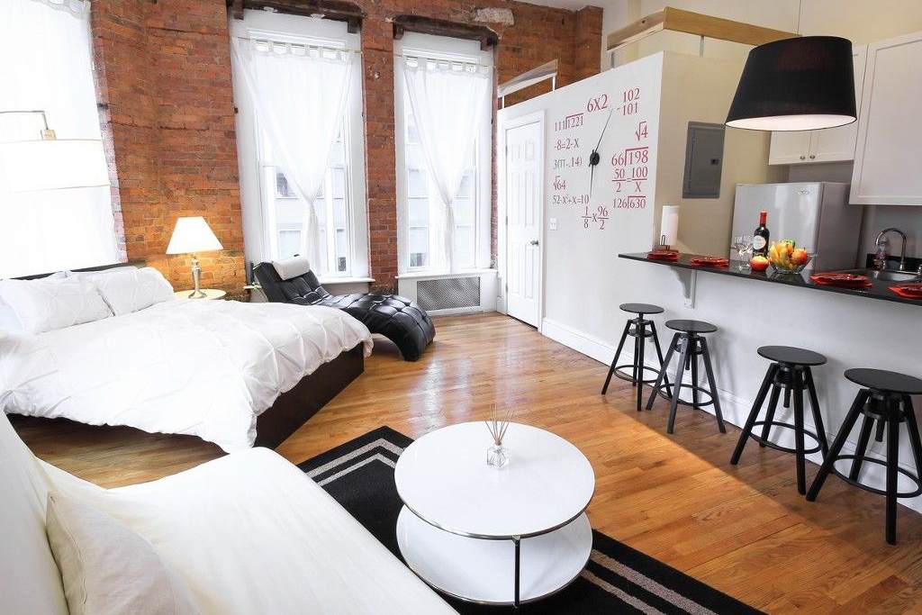 Modern loft apartment with brick wall and white kitchen and double bed and sofa bed